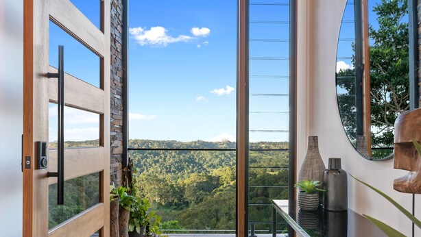 A modern interior with a glass door leading to a balcony with a scenic mountain view. - The Ridge at Maleny (Booroobin)
