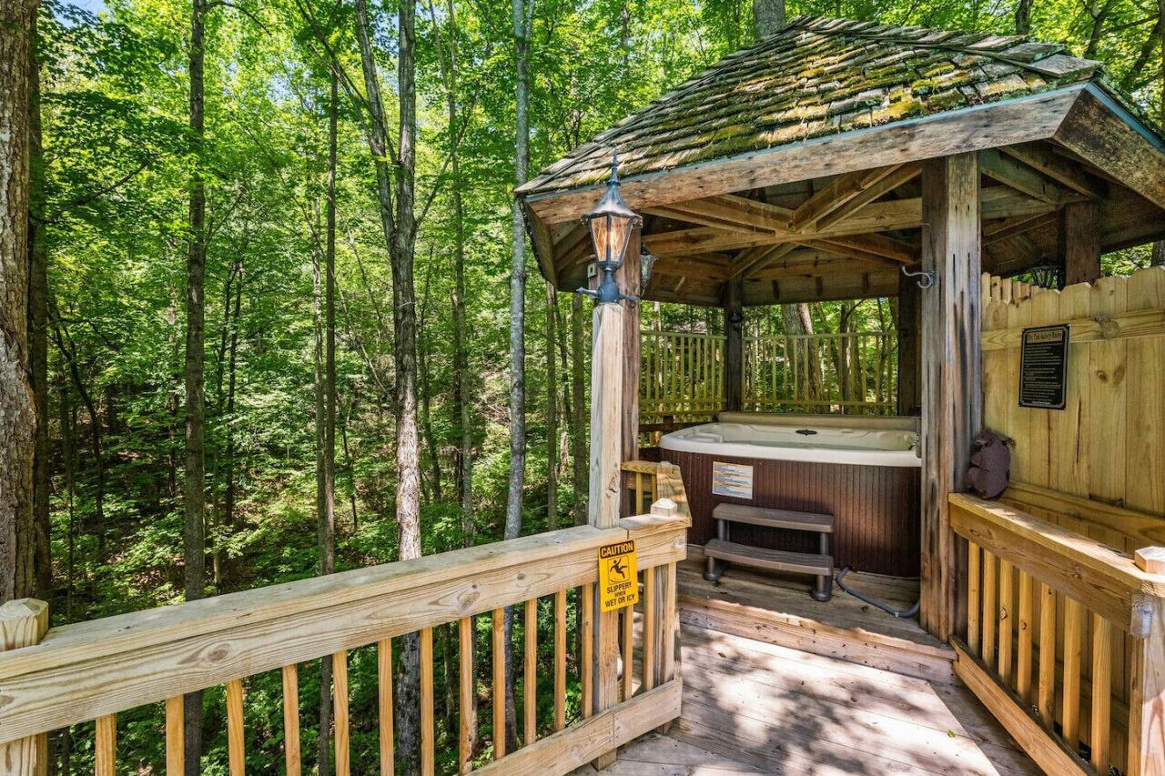 Ein Holz-Hottub-Gebilde mit einer Holzterrasse und Geländern, umgeben von einem Wald.