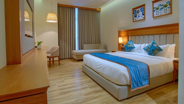 Habitación de hotel con una cama grande, un escritorio, una silla y un televisor.