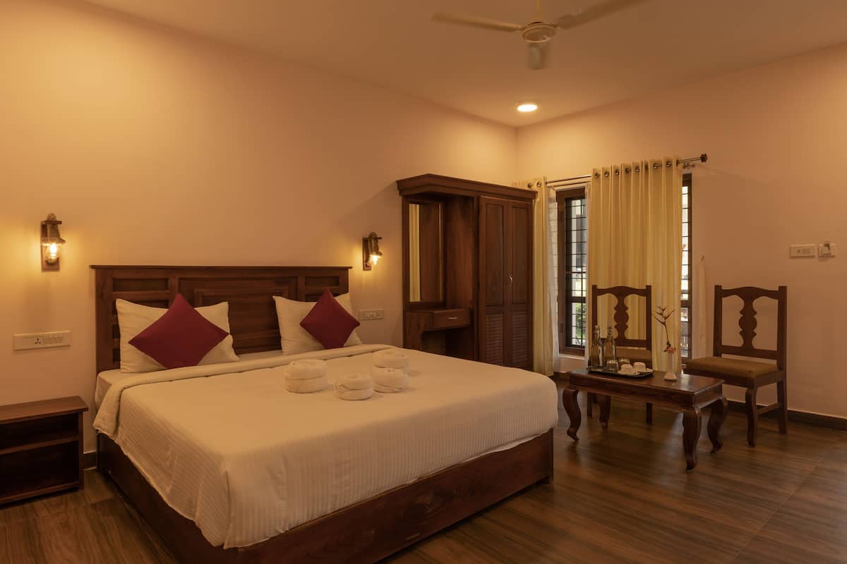 A bedroom with a wooden bed, bedside tables, a nightstand, a ceiling fan, a window with curtains, and a wooden chair.