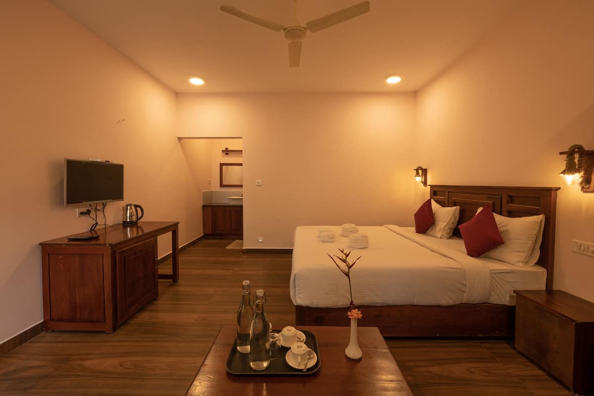 A hotel room with a bed, bedside table, and a television on a cabinet.