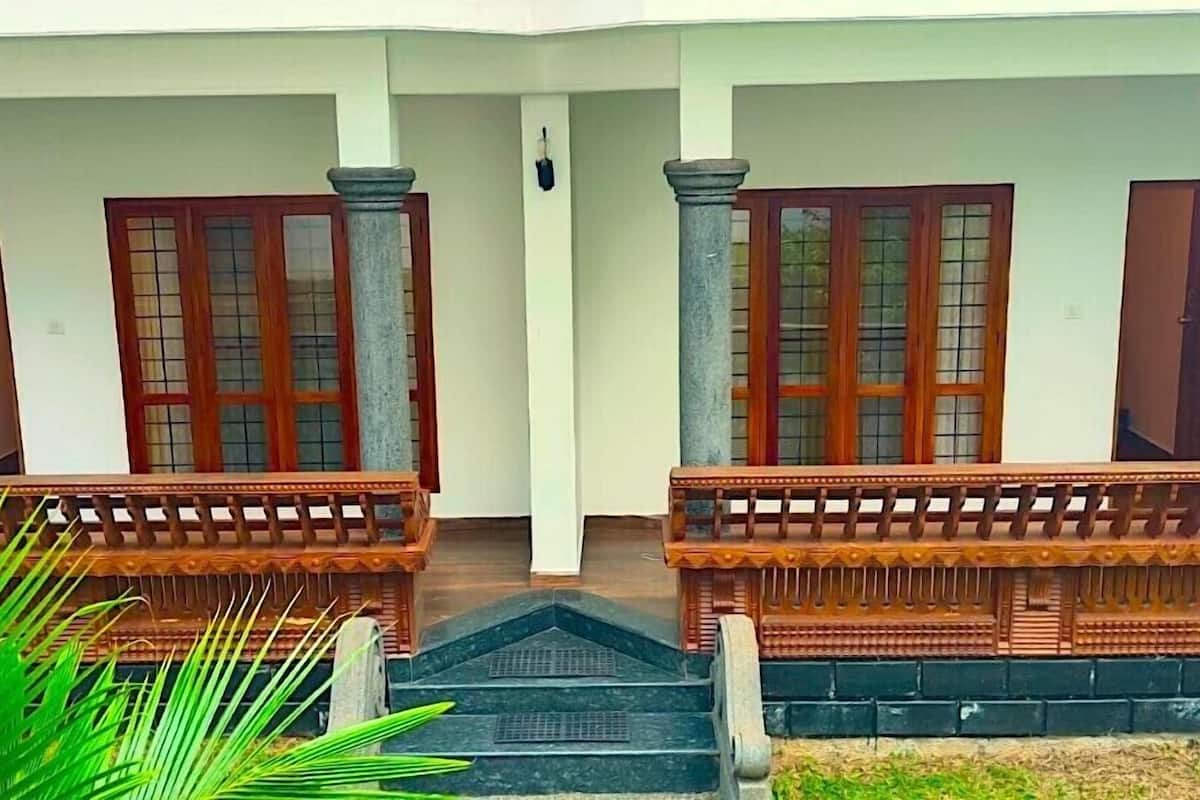 A building with two columns, wooden doors with glass panels, and a staircase leading to an upper level.