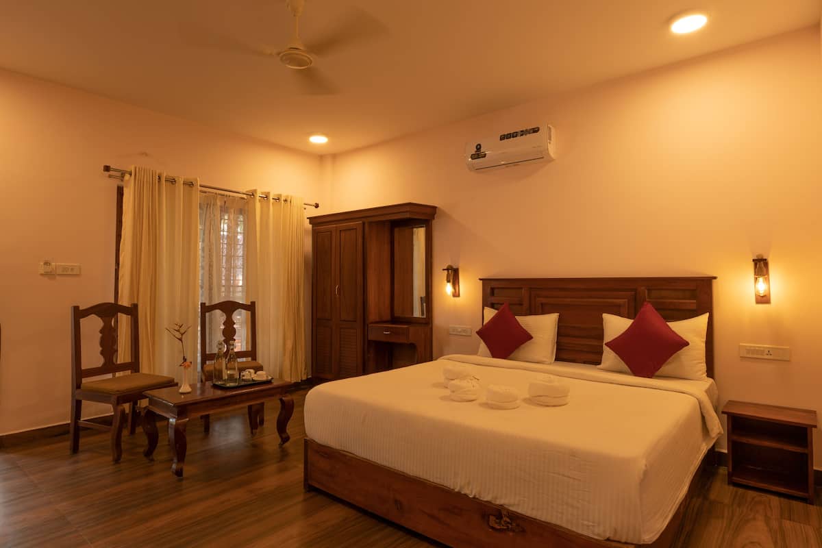 A hotel room with a large bed, wooden furniture, and an air conditioning unit.