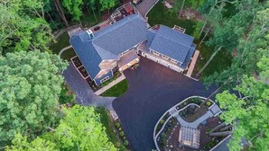An aerial view of a house surrounded by dense trees, with a driveway leading to a garage and a circular driveway with a small structure. - The Athena hideaway - hottub, firepit, lake & racetrack (Saratoga Springs)