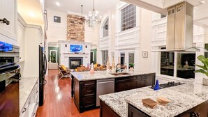 A spacious kitchen with a large island, dark cabinetry, and a stone accent wall. - The Athena hideaway - hottub, firepit, lake & racetrack (Saratoga Springs)