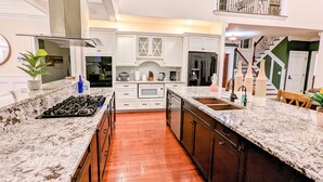 A modern kitchen with white cabinets, a granite countertop, a stainless steel range hood, and a wooden floor. - The Athena hideaway - hottub, firepit, lake & racetrack (Saratoga Springs)