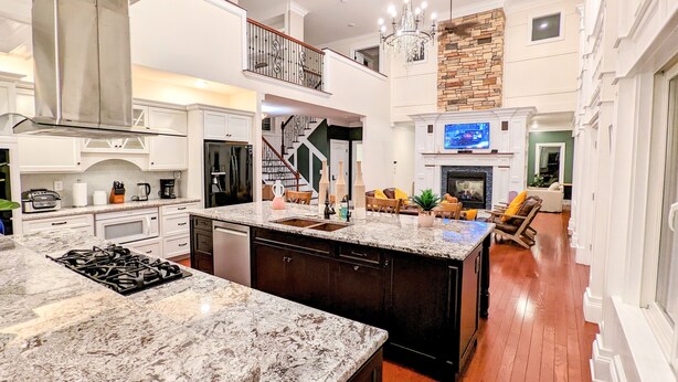 A spacious kitchen with granite countertops, a large island, and a stone fireplace. - The Athena hideaway - hottub, firepit, lake & racetrack (Saratoga Springs)