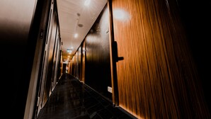A long, narrow hallway with wooden paneling on one side and a dark floor. - D'nova Hotel @ Bugis (Singapore)