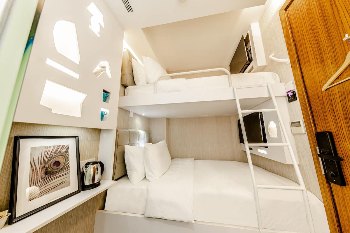 A bunk bed with a ladder, a framed picture, a kettle, and a wooden door.