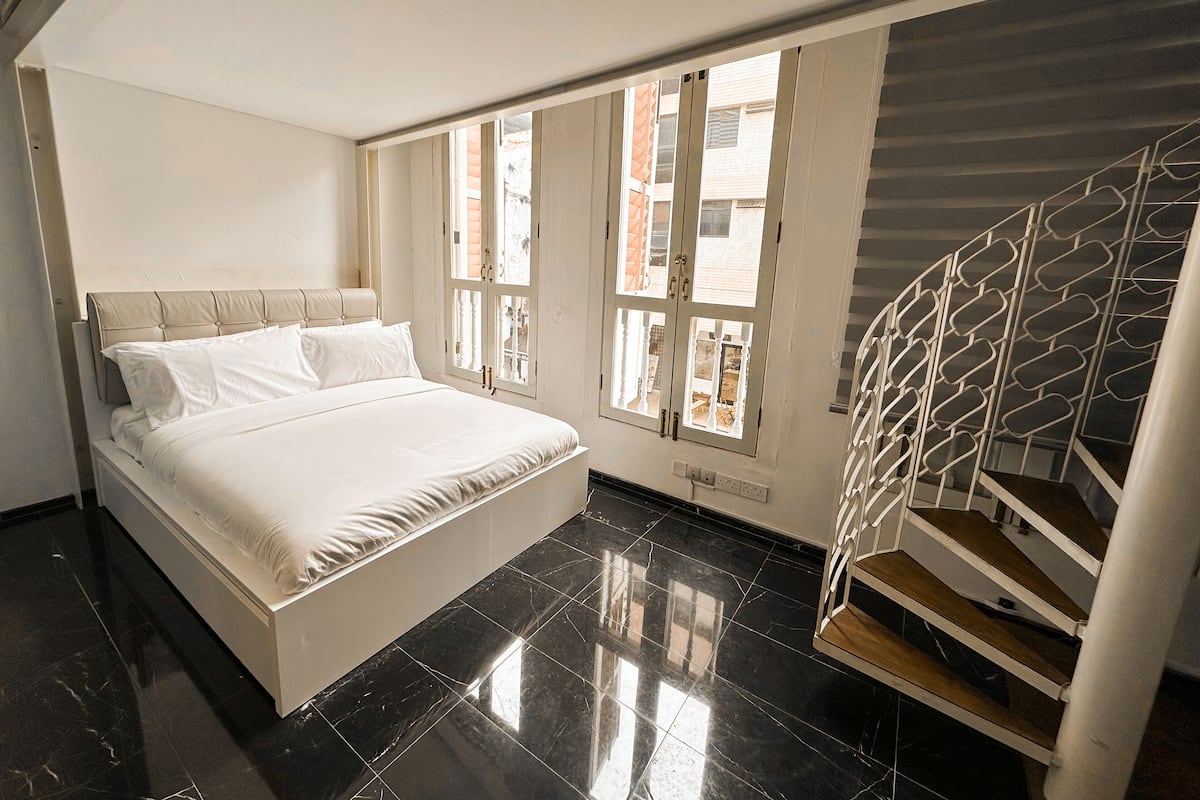 A bedroom with a bed, a window, and a staircase.