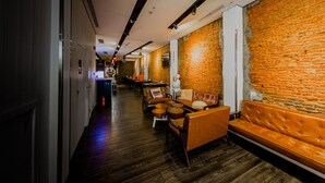 A hallway with a brick wall, wooden flooring, and seating area with a sofa and chairs. - D'nova Hotel @ Bugis (Singapore)