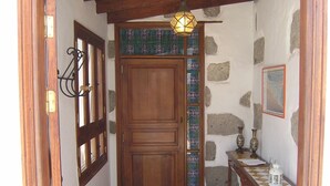 A wooden door with a stained glass window, a stone wall, and a small table with a lantern.
