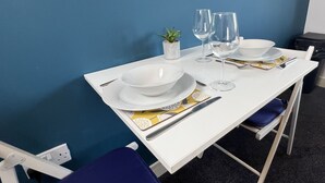 A dining table set with white plates, bowls, cutlery, and wine glasses, against a blue wall. - 6 Cross Court, Stafford (Stafford)