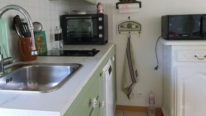 A kitchen with green cabinets, a microwave, a sink, and a clock on the wall. - Meublé de tourisme classé 3* 35 m2 + terrasse. 2 pers, countryside VEXIN FRANçAIS (Guernes)