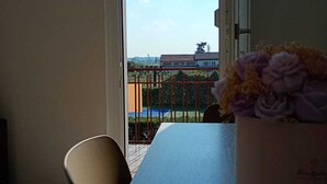 A balcony with a view of a swimming pool and buildings, a table with a vase of flowers, and a chair. - Casa Viola: Your Relaxing Retreat by the Lake (Pacengo)