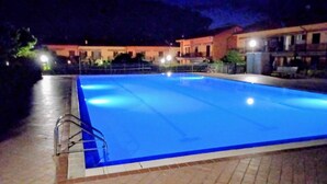 A swimming pool at night with a metal ladder on one side.