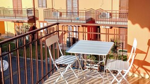 A balcony with a table and chairs, a view of neighboring buildings, and a clear sky. - Casa Viola: Your Relaxing Retreat by the Lake (Pacengo)