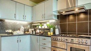 Une cuisine moderne avec des meubles de couleur bleu clair, une cuisinière en acier inoxydable et un plan de travail en marbre.