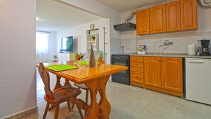 A compact kitchen with wooden cabinets, a dishwasher, and a dining area with a wooden table and chairs.