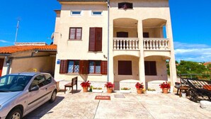 A two-story building with a balcony and a car parked in front.