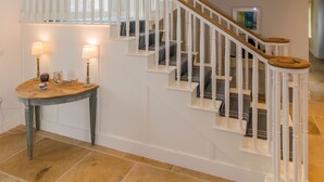 Un escalier spacieux avec des rampes blanches et des marches en bois, menant à l’étage supérieur.