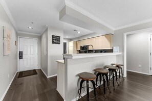 A modern kitchen with a bar area, wooden flooring, and a white door. - Charming 4-bedroom condo at The Champions (Branson)