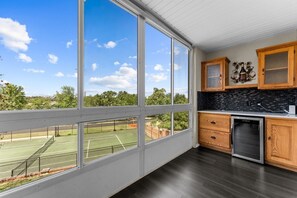 A kitchen with large windows, a tennis court, and wooden cabinets.
