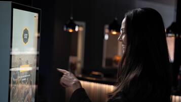 Una persona interactuando con un quiosco digital en un espacio interior con poca luz.