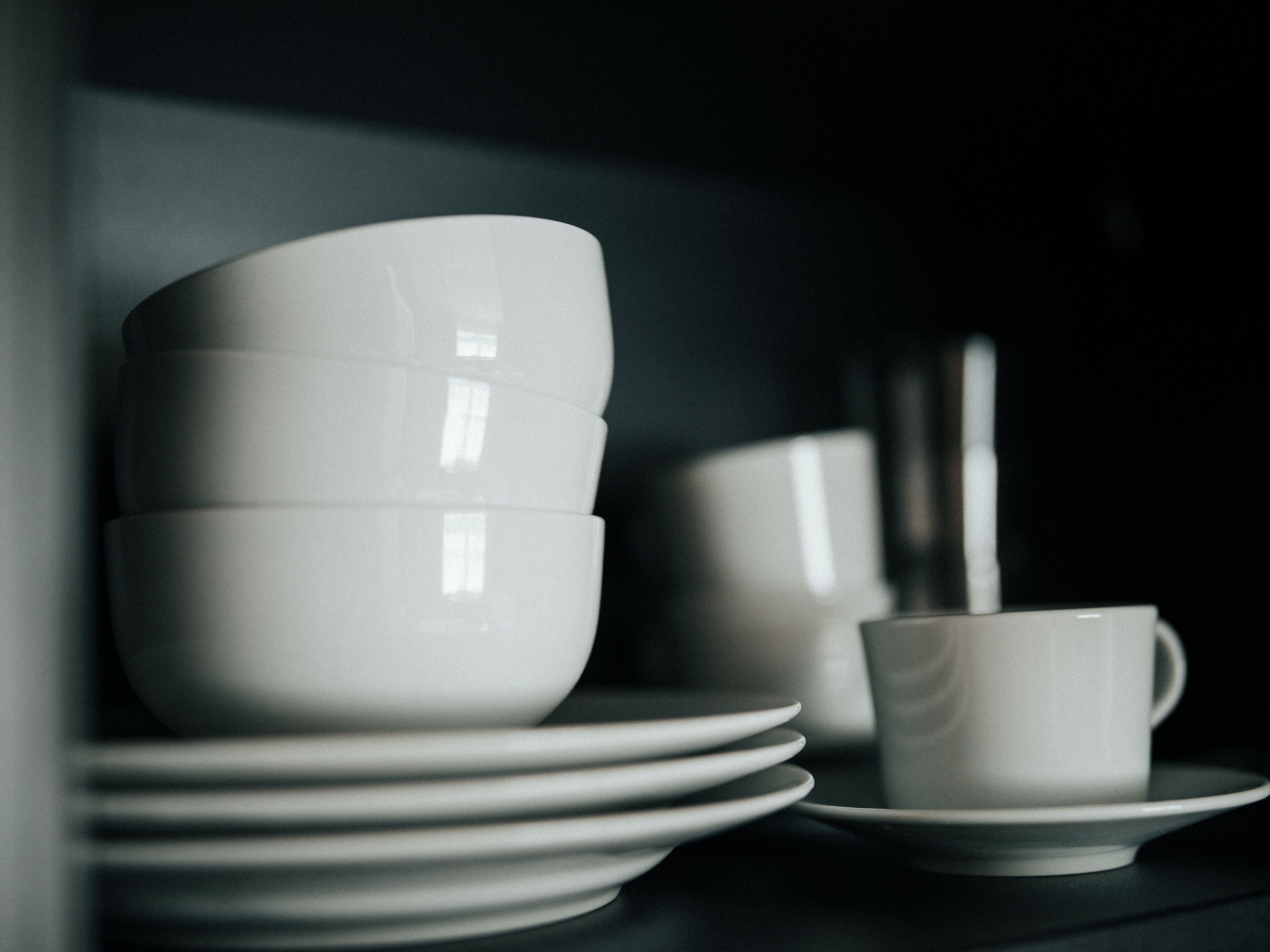 A stack of white bowls and plates on a dark surface.