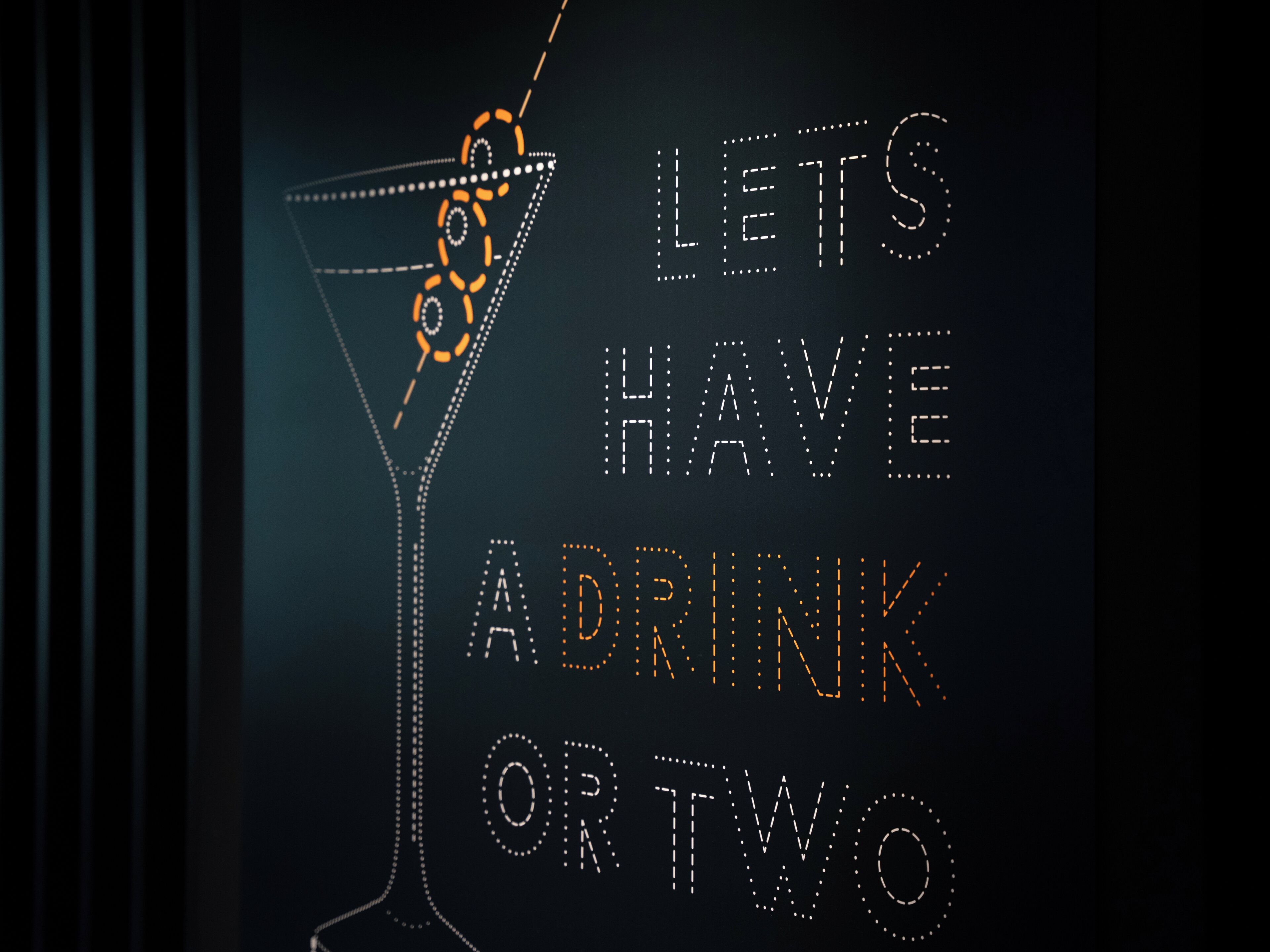 A cocktail glass with a decorative pattern and the text "LETS HAVE A DRINK OR TWO" on a dark background.