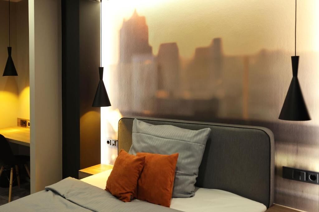 Een hotelkamer met een bed, een bureau en twee hanglampen.