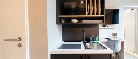 Una cocina compacta con microondas, fregadero y armarios.