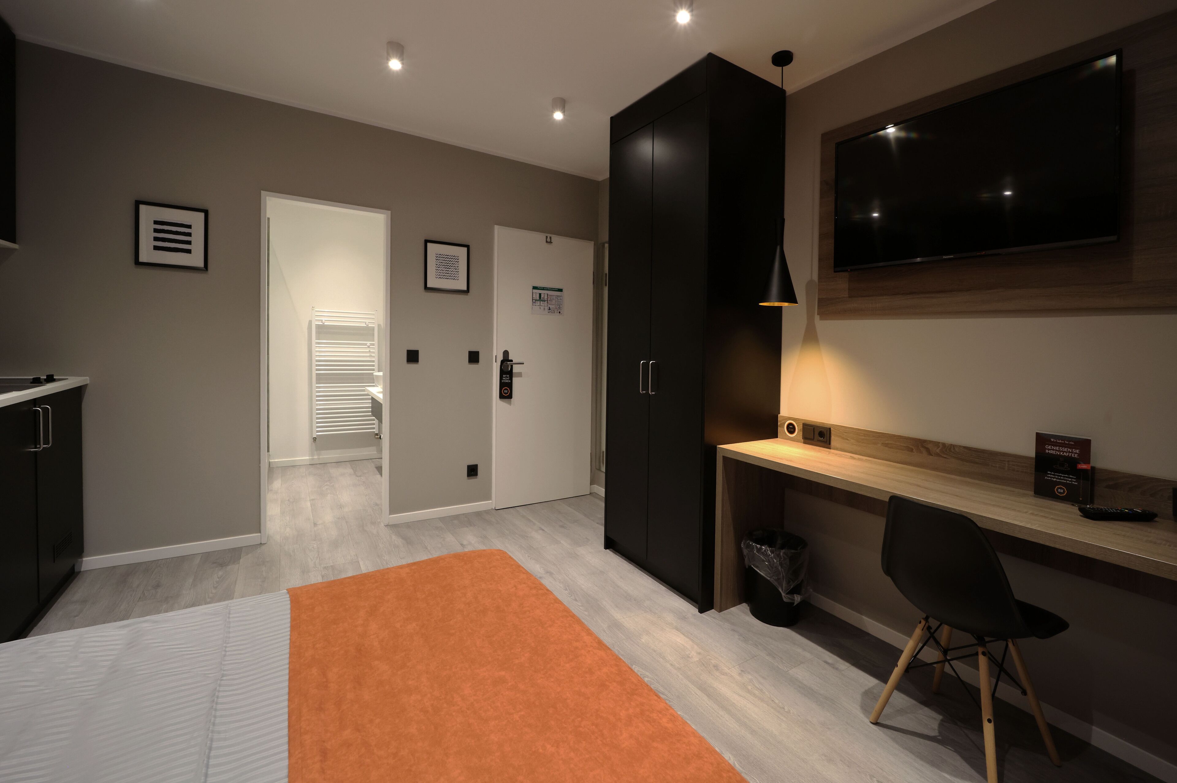 A modern room with a desk, a TV, and a wardrobe.