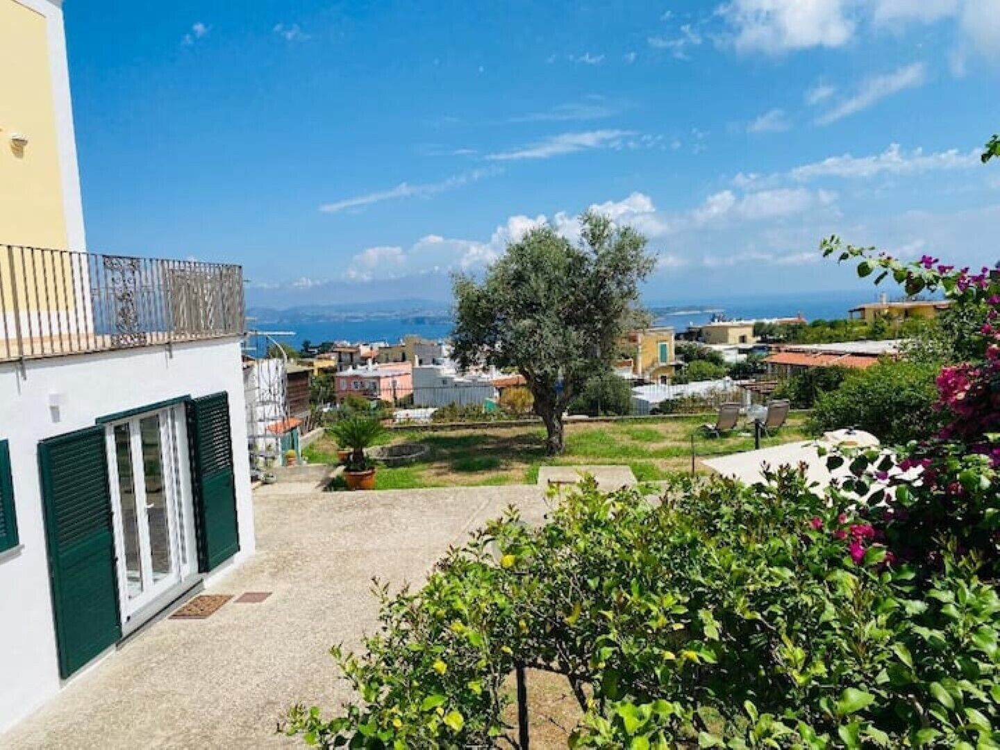 Zona residenziale con vista sul mare, un albero grande e un balcone con ringhiera.
