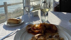 A dining table with a plate of food, two wine glasses, and a bottle of water. - Wow☀️☀️☀️☀️☀️ Beachfront apartment, panoramic views, amazing sunsets, XL pool! (Marbella)