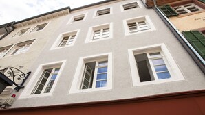 A multi-story building with white-framed windows and a red brick base. - Boutique Apartment Vino e Amore (Freiburg im Breisgau)