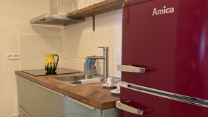 A compact kitchen with a red refrigerator, a wooden countertop, a stainless steel sink, and a glass cabinet. - Boutique Apartment Vino e Amore (Freiburg im Breisgau)