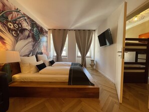 A hotel room with a large bed, a TV mounted on the wall, and a decorative wall mural. - Boutique Apartment Vino e Amore (Freiburg im Breisgau)
