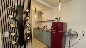 A kitchen with a wine rack, a red refrigerator, a fan, and a wooden floor. - Boutique Apartment Vino e Amore (Freiburg im Breisgau)