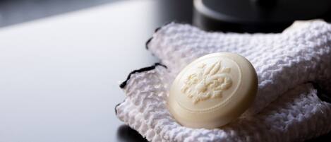 A white candle on a textured cloth on a dark surface, with a round mirror in the background.
