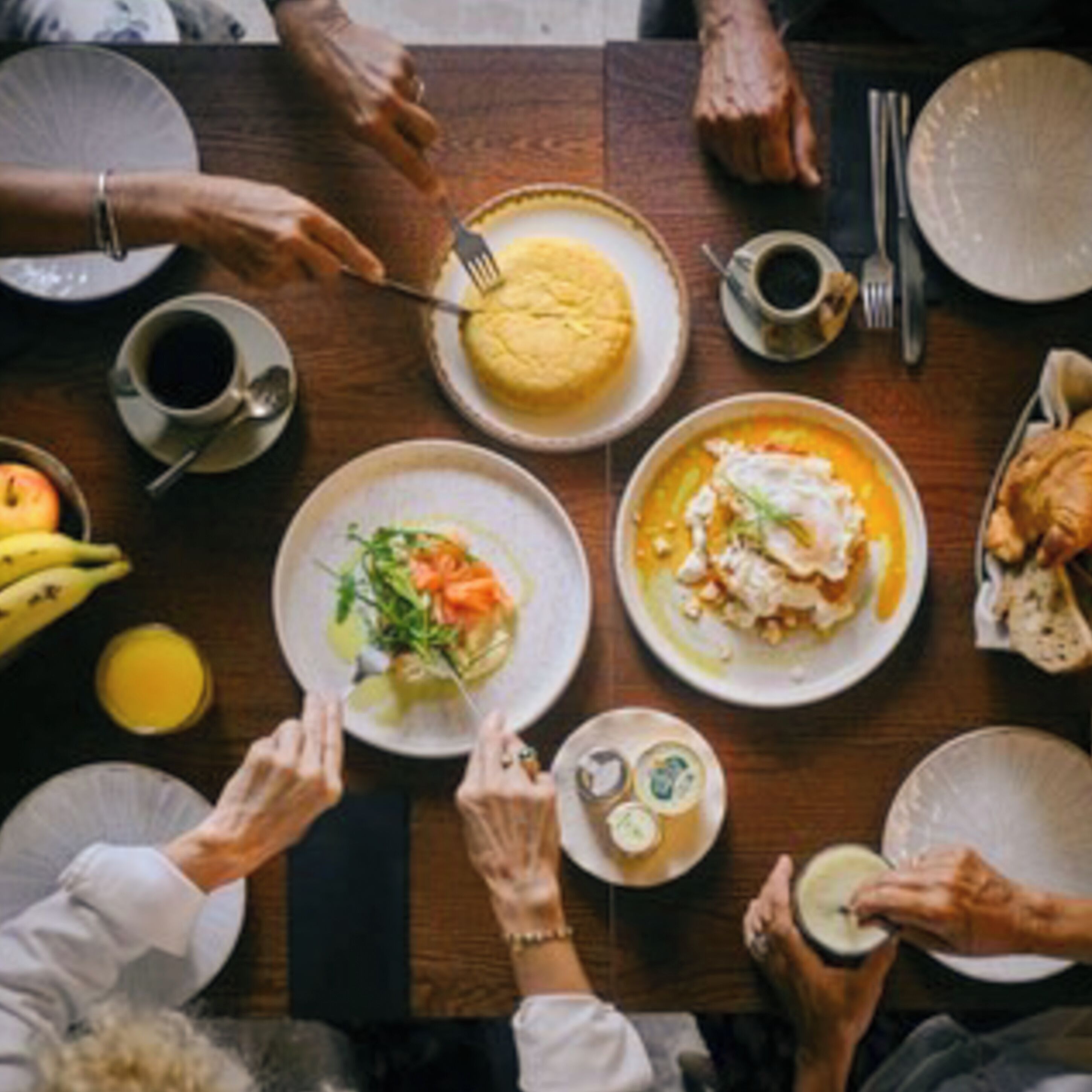 A dining table with various dishes, utensils, and a cup of coffee.