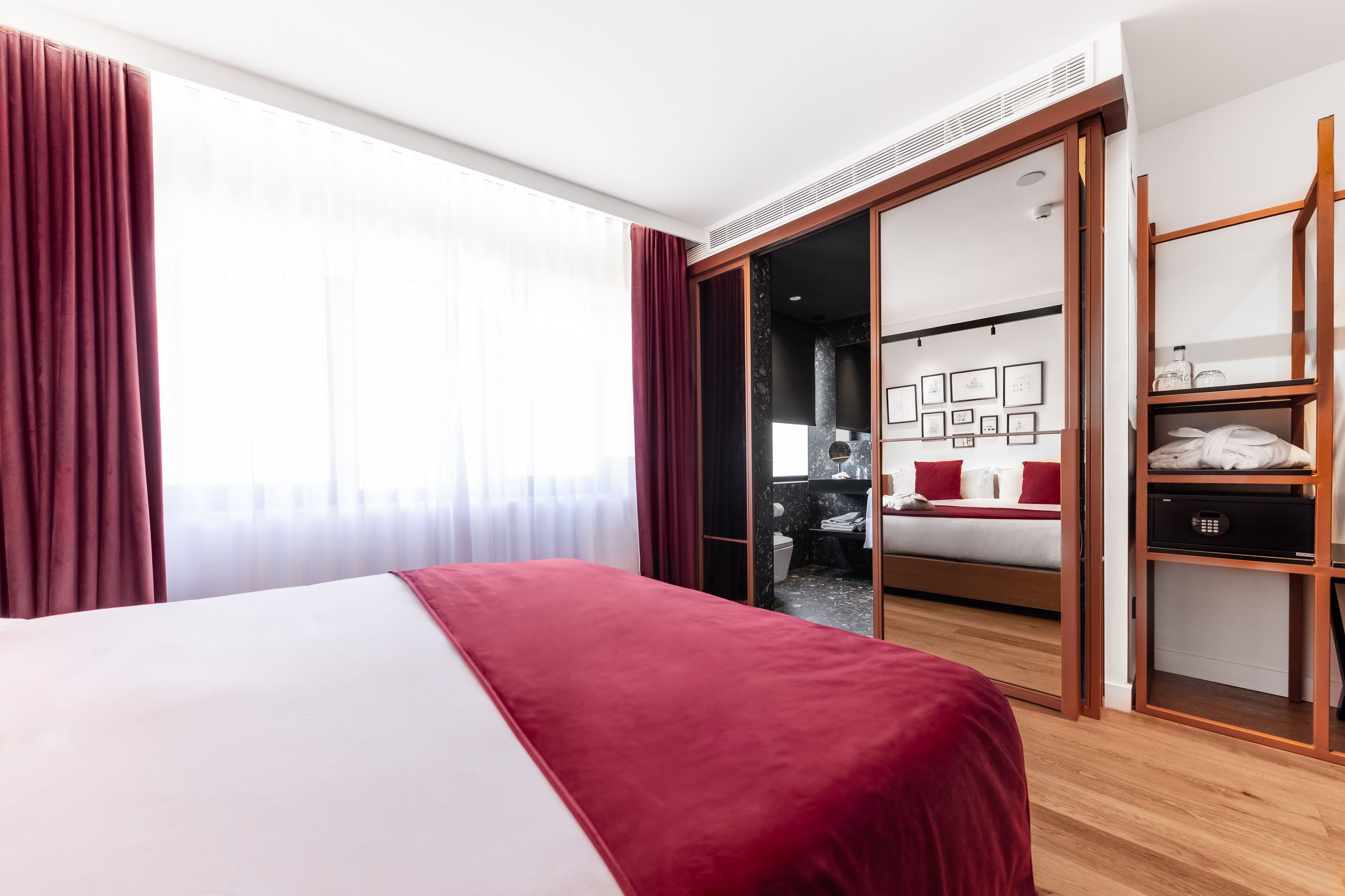 Habitación de hotel con cama, armario y baño visible a través de una puerta abierta.
