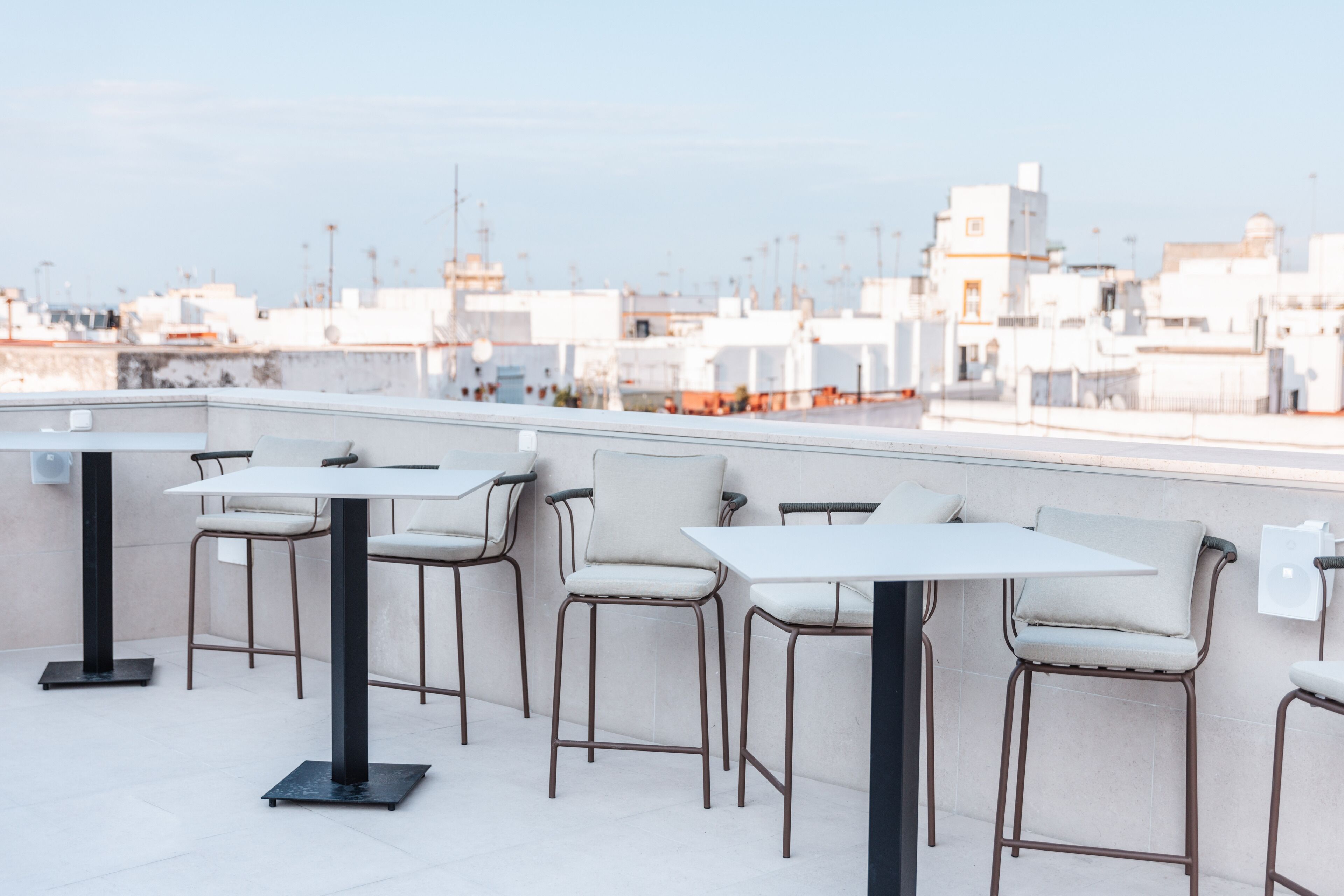 A rooftop terrace with tables and chairs, offering a view of the cityscape.