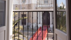 Vista de un edificio histórico con arquitectura clásica, una escalera roja y una barandilla de metal.