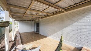 A covered patio area with a brick floor, white brick walls, and a metal roof structure. - Cabana Feliz - Lifestyle Yamba (YAMBA)