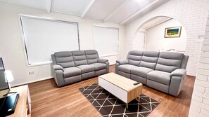 A modern living room with two grey sofas, a wooden coffee table, and a patterned rug. - Cabana Feliz - Lifestyle Yamba (YAMBA)