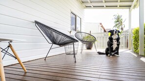 Una terraza de madera con dos sillas de estructura metálica negra y una planta en maceta.