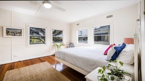 A bedroom with a bed, a bedside table, a window, and a ceiling fan.