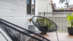 A balcony with a chair, a small table, and a potted plant.
