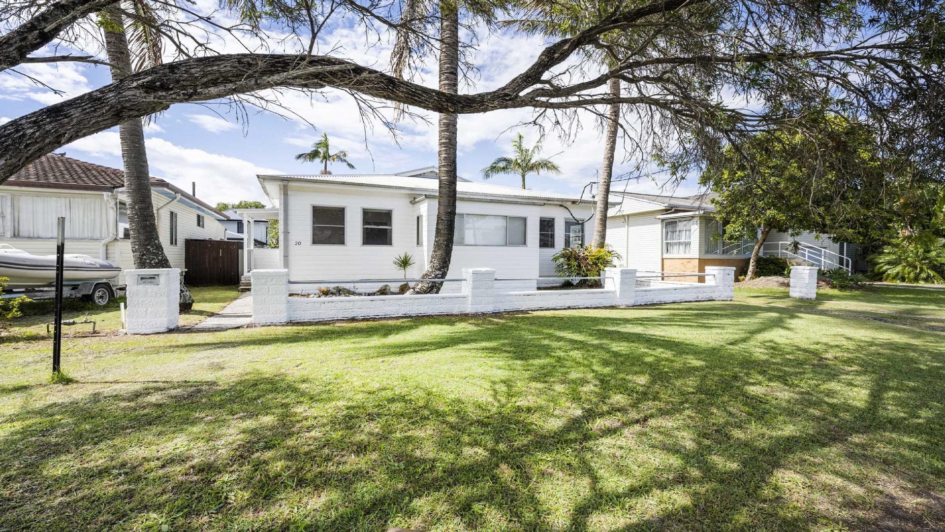A single-story house with a white exterior, a front porch, and a well-maintained lawn.